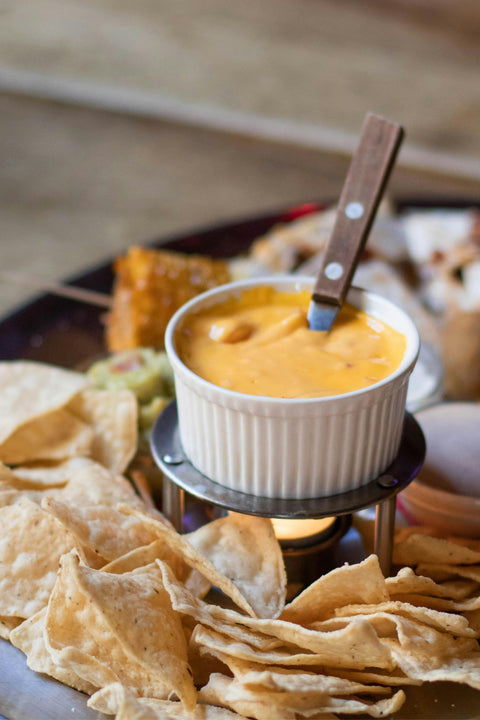 small bowl of chile con queso with white tortilla chips in the foreground